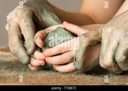 Le mani delle donne di guida di un bambino le mani per aiutarlo a lavorare con la creta Foto Stock