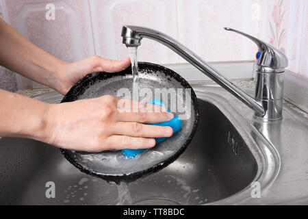 Le mani della donna il lavaggio la padella nel lavandino, primo piano Foto Stock