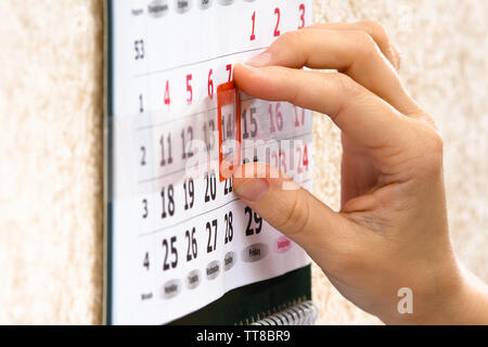 Donna mettendo mano contrassegno rosso sul calendario la data, primo piano Foto Stock