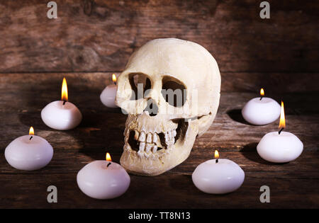 Natura morta con teschio umano e candele su sfondo di legno Foto Stock