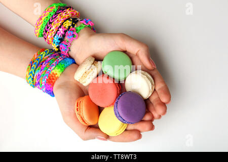 Mani femminili con bracciali e pila di amaretti isolato su bianco Foto Stock