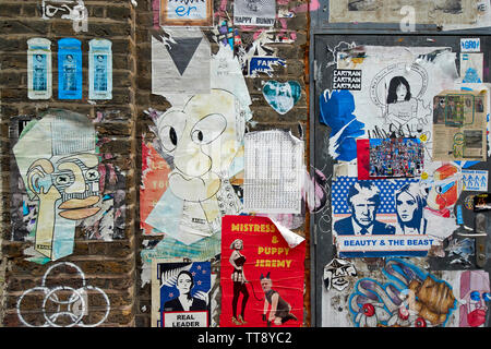 Londra Inghilterra Brick Lane poster e graffiti su un vecchio muro di mattoni Foto Stock