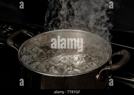 Acqua bollente in pentola di vetro trasparente sul piano cottura Foto stock  - Alamy