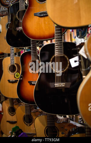 Stringa di metallo chitarre acustiche appesi alle pareti del music store pronto a eseguire Foto Stock