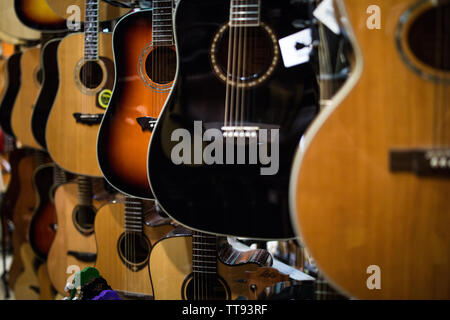 Stringa di metallo chitarre acustiche appesi alle pareti del music store pronto a eseguire Foto Stock