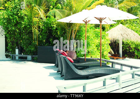 I lettini in resort su verdi palme in background Foto Stock