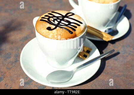 Tazze di cappuccino con chiave di violino su schiuma sul tavolo nella  caffetteria