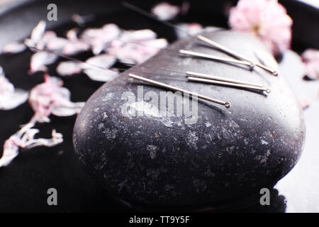 Aghi di agopuntura con spa pietra sul vassoio, primo piano Foto Stock