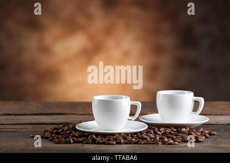 Tazze di caffè e fagioli su sfondo sfocato Foto Stock