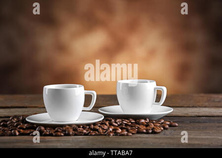 Tazze di caffè e fagioli su sfondo sfocato Foto Stock