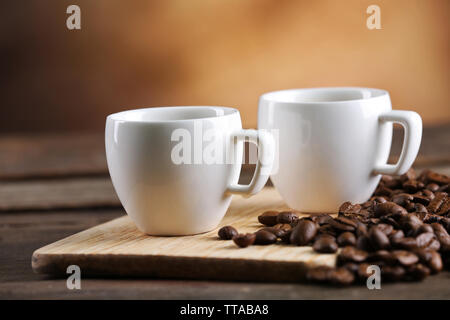 Tazze di caffè e fagioli su sfondo sfocato Foto Stock