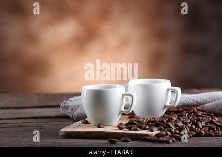 Tazze di caffè e fagioli su sfondo sfocato Foto Stock