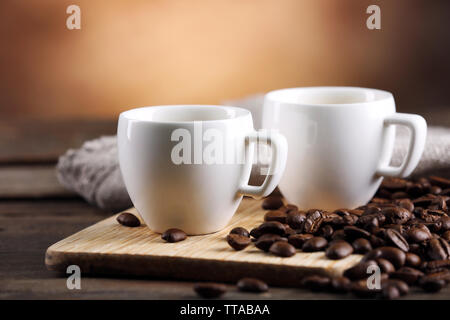 Tazze di caffè e fagioli su sfondo sfocato Foto Stock