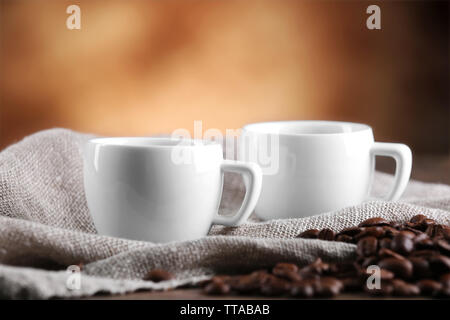 Tazze di caffè e fagioli su sfondo sfocato Foto Stock