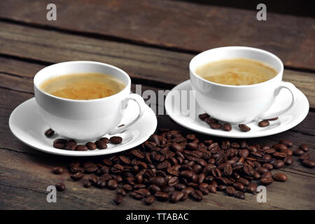 Tazze di caffè e fagioli sul tavolo di legno vicino fino Foto Stock