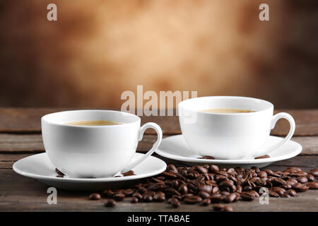 Tazze di caffè e fagioli su sfondo sfocato Foto Stock