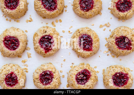 Vista superiore piana dei laici Confettura di lamponi di fiocchi d'avena e i cookie di identificazione personale seduto su un bianco Foglio di cottura Foto Stock