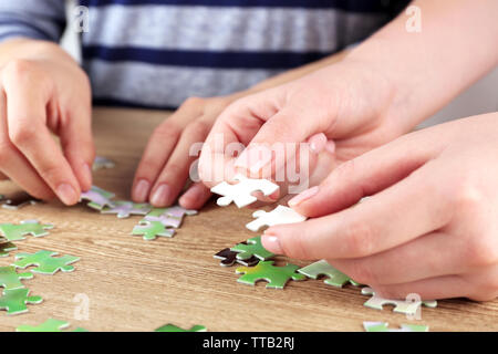Mani femminili puzzle di montaggio su tavolo in legno, primo piano Foto Stock