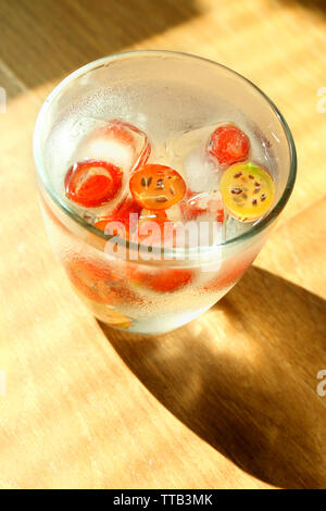 Vetro a freddo estivo rinfrescante drink con bacche e cubetti di ghiaccio sul tavolo vicino fino Foto Stock