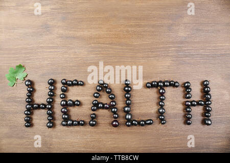 Salute parola fatta di ribes nero su sfondo di legno Foto Stock