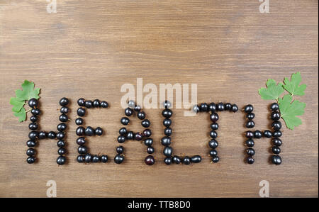 Salute parola fatta di ribes nero su sfondo di legno Foto Stock