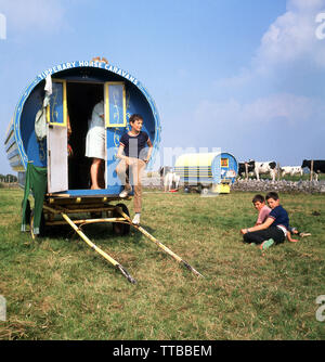 Anni sessanta, storiche, i bambini al di fuori della loro casa vacanze estate, a Tipperary Horse Caravan, una prua tradizionale top gypsy carro parcheggiato in un campo in Swanston farm, nei pressi di Edimburgo, Scozia. Un vecchio villaggio Swanston è pre-prevalentemente rurale, ma vicino alle zone residenziali della città scozzese. Foto Stock