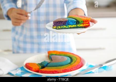 Giovane donna tenendo la piastra con la porzione di rainbow torta in cucina Foto Stock