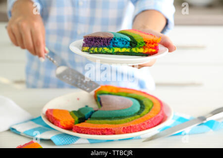 Giovane donna tenendo la piastra con la porzione di rainbow torta in cucina Foto Stock