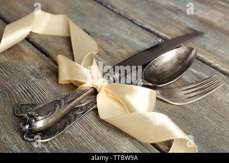 Posate legate con nastro su sfondo di legno Foto Stock