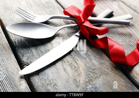 Posate legate con nastro su sfondo di legno Foto Stock