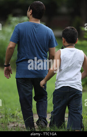 Vista posteriore di un uomo con il suo figlio a camminare in un parco Foto Stock
