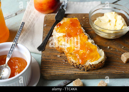 Gustose marmellate nella ciotola, burro, pane fresco e tablet sul blu sullo sfondo di legno Foto Stock