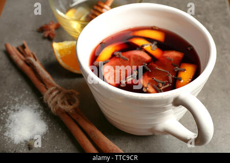 Gustoso vino brulé in tazza di ceramica con agrumi e cannella sul tavolo Foto Stock