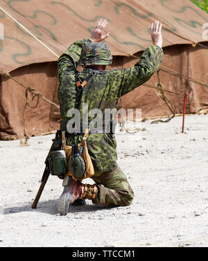 Un reenactor vestito come un tedesco di seconda guerra mondiale Waffen SS Soldier arrendersi Foto Stock