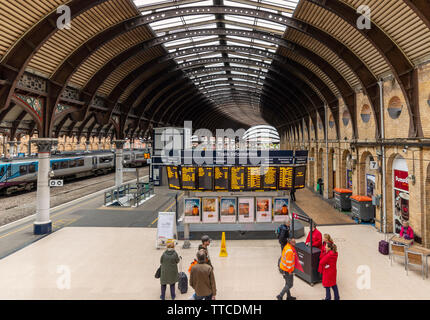 Un sistema elettronico di bacheca presso la stazione ferroviaria di York dando tempi di treno Partenze e arrivi Passeggeri verificare orari e un treno attende prima di partire. Foto Stock