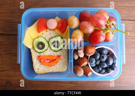 Sandwich di Creative con frutta e noci in lunchbox su sfondo di legno Foto Stock