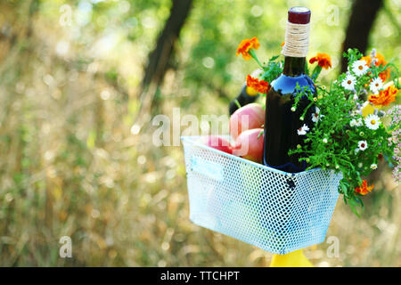 Bicicletta con fiori e una bottiglia di vino nel cestello di metallo closeup, all'aperto Foto Stock