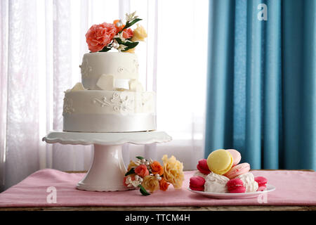 Bella torta nuziale decorata con fiori di colore rosa sul tavolo nella camera Foto Stock