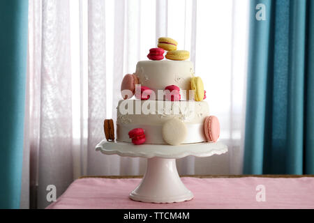 Bella torta nuziale decorata con fiori di colore rosa sul tavolo nella camera Foto Stock