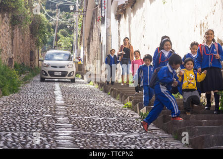 Scena di strada Cusco bambini - scolari a piedi giù per la stretta strada ripida in Cusco, Perù, Sud America. Foto Stock