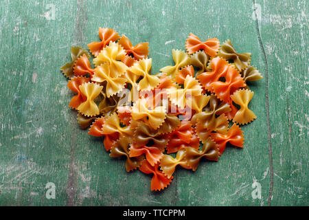 Cuore di pasta a forma di prua sul vecchio sfondo di legno Foto Stock