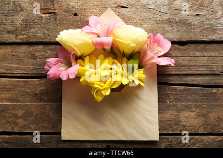 Freschi bouquet di fiori in busta su sfondo di legno Foto Stock