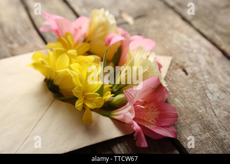 Freschi bouquet di fiori in busta su sfondo di legno Foto Stock