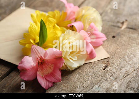 Freschi bouquet di fiori in busta su sfondo di legno Foto Stock