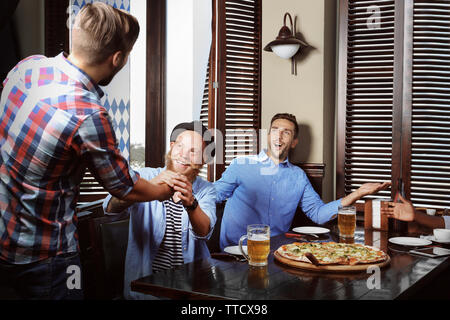 I giovani uomini a bere birra e parlare in cafe Foto Stock