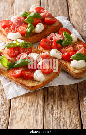 Italian panini con mozzarella, pomodoro, prosciutto e basilico vicino sul piano verticale. Foto Stock