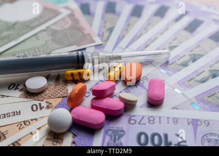 Assistenza sanitaria in India - Il concetto di salute e di business che mostra Indian carta moneta note, pillole, siringa. Foto Stock