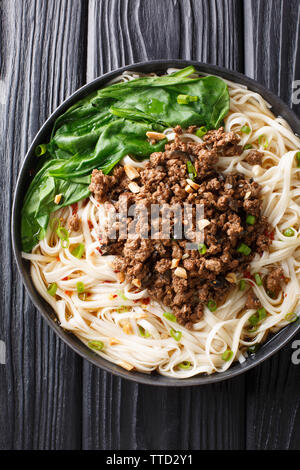 Cinese tradizionale Sichuan Dan Dan Tagliatelle con carne macinata e verdi in una piastra sul tavolo. Verticale in alto vista da sopra Foto Stock