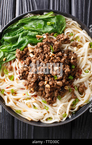 Dan Dan Noodles - saporito e Sichuan piccante tagliatelle servita con la carne di suolo closeup sulla piastra della tavola. Verticale in alto vista da sopra Foto Stock