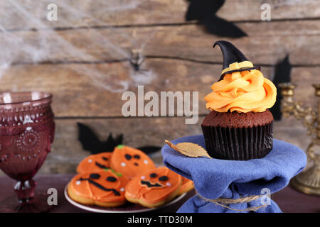 Tortina di Halloween e biscotti sul tavolo sulla parete in legno sfondo Foto Stock